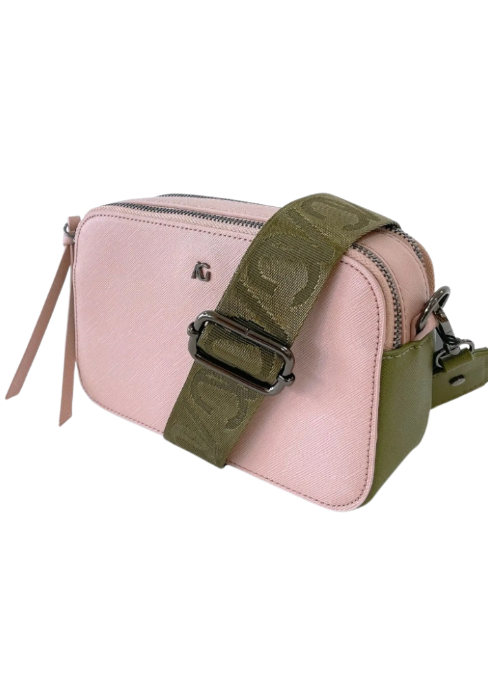 A pink vegan leather crossbody bag with silver zippers and a wide olive green strap featuring a subtle embossed pattern. The bag has a sleek, minimalist design with a small silver logo on the front. The combination of pastel pink and earthy green creates a stylish and versatile accessory.