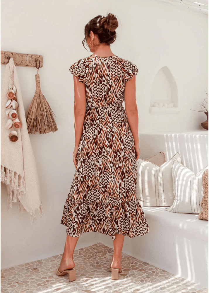 A women’s mid-length dress with an abstract animal print design in shades of brown, white, and black, featuring flutter sleeves and a tiered skirt. The dress exhibits a V-neckline and a cinched waist.